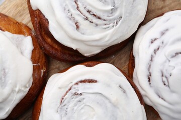 Tasty cinnamon rolls with cream as background, closeup
