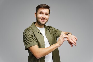 Man smiling while adjusting smartwatch in a neutral studio background during a bright, lively moment