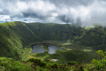Crater of Vulcão da Caldeira or The Caldeira Volcano on Faial Island, the Azores, in the Atlantic Ocean. Stratovolcano with a lake inside the crater. Low clouds. Hiking around volcano.