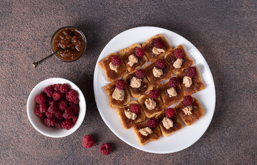 Canapes with foie gras, fig dip and fresh raspberries on white plate