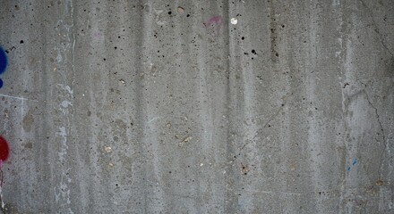 Concrete Texture with Graffiti Traces: A detailed close-up shot reveals the raw texture of a weathered concrete wall, subtly marked with faded traces of blue and red graffiti.