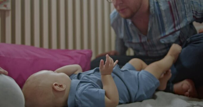 A happy baby enjoys playtime with mom and dad at home. They make silly faces and tickle their adorable child.