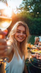 Vertical portrait of a beautiful blonde woman with a glass of wine, summer sunset bbq party pov