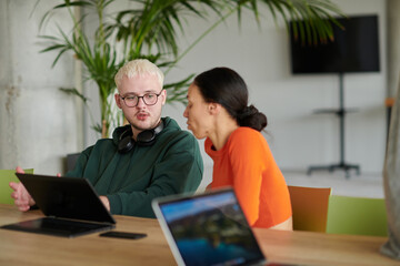 Obraz premium A blond businessman and his colleague sit in an office discussing work while using a laptop to collaborate on tasks