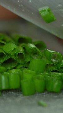Camera movement on hands cut fresh green onions with kitchen knife. Cooking food with greens. Greens, vegetables. Vertical shot