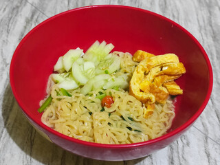 A bowl of Indonesian noodle soup with vegetables and egg.