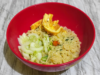 A bowl of Indonesian noodle soup with vegetables and egg.