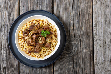 pasta rings topped with braised meat in bowl