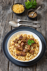 pasta rings topped with braised meat in bowl
