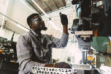 african black male worker working in heavy metal industry factory punching stamping steel machine
