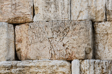 Closeup, detail of textured, old, rows of cracked stones making up a section of the Western Wall in the Old City of Jerusalem, Israel.