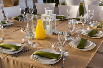 Elegantly set table with wine and water glasses, cutlery and napkins on a pressed cloth at a wedding banquet.