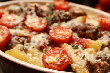 Delicious pasta casserole with cheese, tomatoes, minced meat and thyme in baking dish, closeup