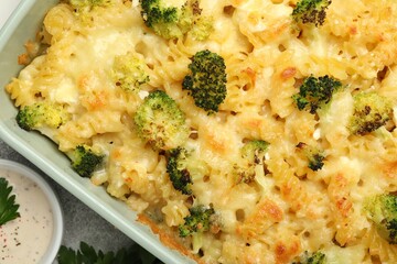 Tasty pasta casserole with cheese, broccoli and sauce on table, top view