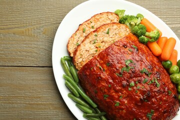 Delicious baked turkey meatloaf with vegetables on wooden table, top view. Space for text