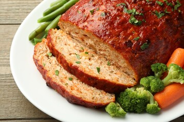 Delicious baked turkey meatloaf with vegetables on wooden table, closeup