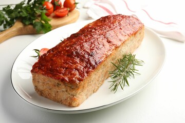 Delicious baked turkey meatloaf, rosemary, cherry tomatoes and parsley on white table, closeup