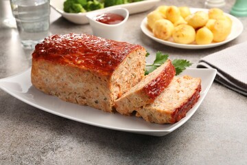 Delicious baked turkey meatloaf with vegetables served on grey table, closeup