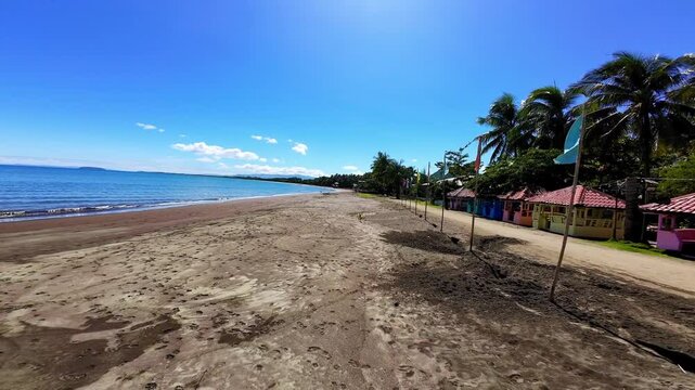 A vibrant scene in Bacuag, Surigao Del Norte, Philippines showcasing a bright orange concrete Bacuag sign set against clear blue skies. This picturesque spot on the golden sandy beaches is a favorite 