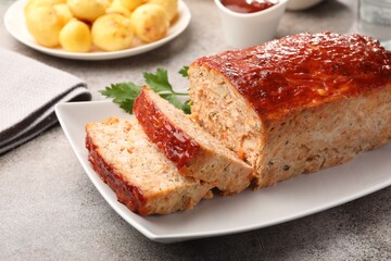 Delicious baked turkey meatloaf with vegetables served on grey table, closeup