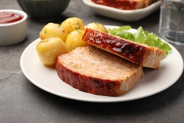 Delicious baked turkey meatloaf with potatoes served on grey table, closeup