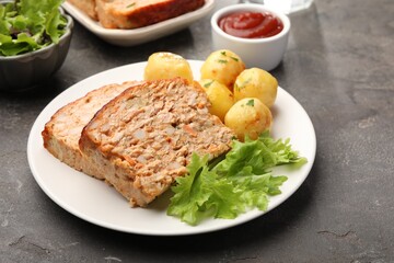 Delicious baked turkey meatloaf with potatoes served on grey table, closeup