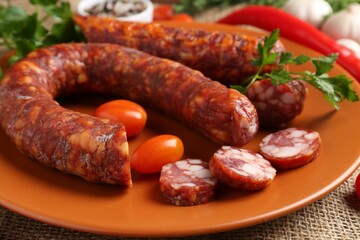 Different smoked sausages, cherry tomatoes and spices on table, closeup