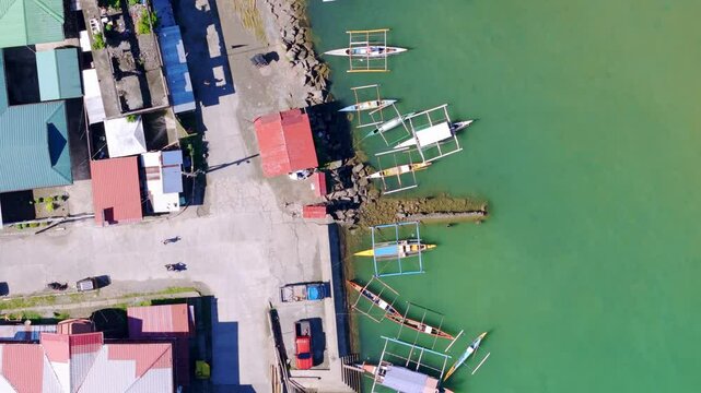 Sunny day birds eye aerial drone footage of pump and banca boats moored at Placer, Surigao Del Norte, highlighting essential transport links between islands and the mainland.