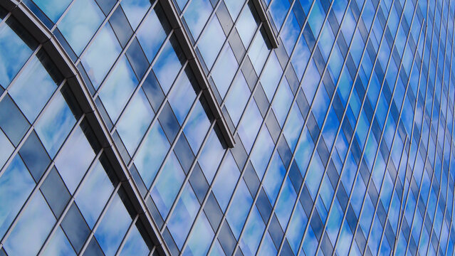 Dynamic Diagonal Reflection..A rhythmic interplay of diagonal glass panels reflecting the soft patterns of a cloudy sky. The architectural detail adds depth and movement to the composition.