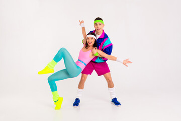 Obraz premium Colorful retro-inspired couple engaging in dynamic partner aerobics against a minimalist white background, embodying vibrant energy