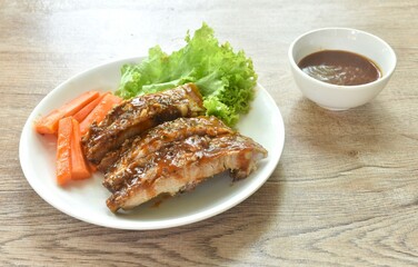 grilled pork rib with carrot and lettuce on plate dipping barbecue sauce cup