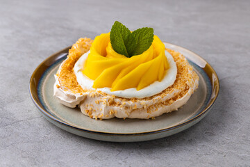 Meringue cake Pavlova with fresh mango and passion fruit and whipped cream on slate, stone or concrete background