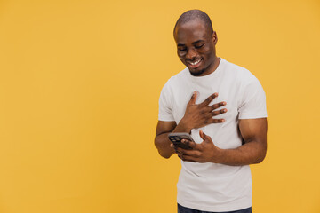 Grateful man holding hand on chest while reading good news on smartphone