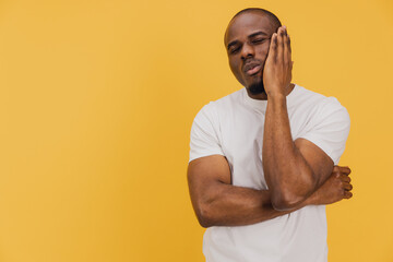 Young African American Man Suffering From Toothache on Yellow Background