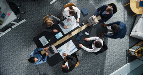 Diverse Professionals Working on Business Statistics Reports and Marketing Plans in an Office. Top Down View of Discussion and Financial Data Analysis on Laptops and Charts. Teamwork and Innovation