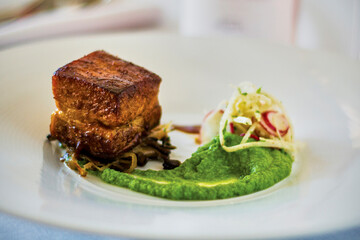 close up shot of braised pork belly with a pea puree