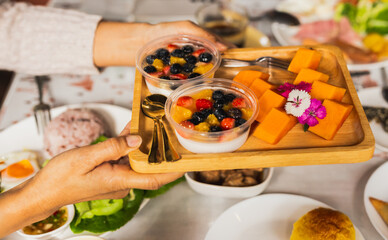 Hnad serving Panna cotta with strawberries and berries friuts.