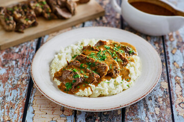 sliced pot roast on a bed of mashed potatoes