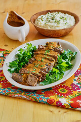 sliced pot roast on a bed of mixed greens