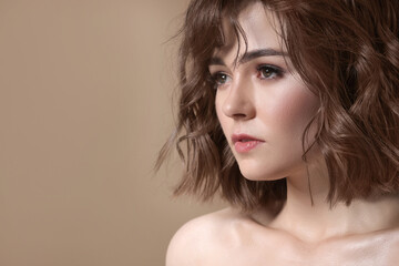 Attractive woman with beautiful hair in mocha mousse shade on dark beige background, space for...