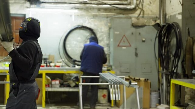 The specialist moves the metal products to the rack. He is dressed in special clothes for safe work at the factory. High quality 4k footage