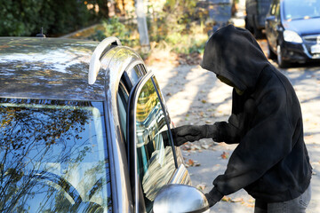 Thief breaking into modern auto. Car hijacking