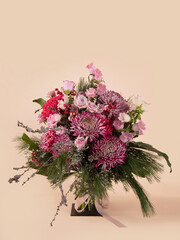 Festive pink and purple floral arrangement with vibrant chrysanthemums, roses, and seasonal greenery, creating an elegant bouquet for holiday and winter celebrations
