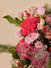 Elegant pink and red floral bouquet with vibrant chrysanthemums, roses, and seasonal greenery, adorned with berries and festive decorations for holiday celebrations