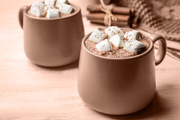 Delicious hot cocoa with marshmallows on table, toned in mocha mousse shade. Trendy color of 2025 year