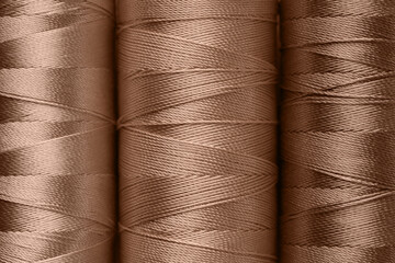 Sewing threads in mocha mousse shades, closeup. Trendy color of 2025 year