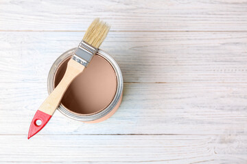 Mocha mousse shade paint in can and brush on white wooden background, top view. Trendy color of 2025 year