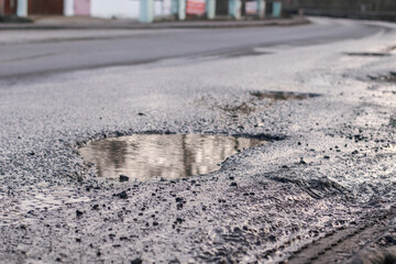 Pothole on asphalt road after rain