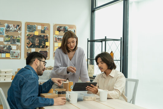 Diverse team collaborating on sustainable packaging concepts with digital tools in creative office - Powered by Adobe