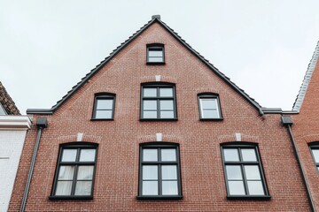 Naklejka premium A brick building featuring numerous windows that highlight its unique architectural style and design stands prominently in an urban setting on an overcast day